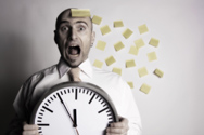 A stressed man with a big clock and post-it sticks
